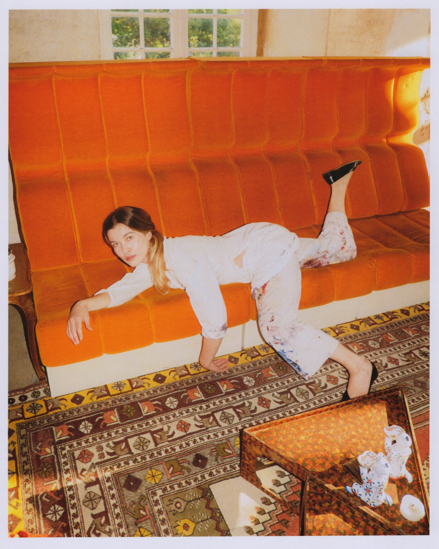 Blanc de Travail trousers worn on an orange velvet sofa